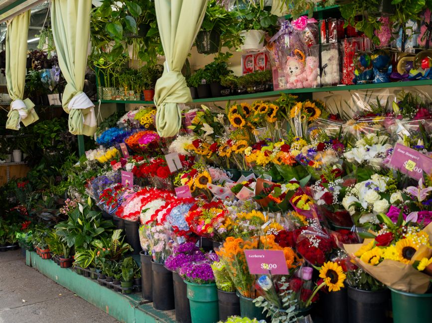 An outdoor floral display at Flowers Crofton Park showcasing an array of fresh flower bouquets and arrangements. The display includes vibrant sunflowers, roses, lilies, and mixed seasonal flowers wrap